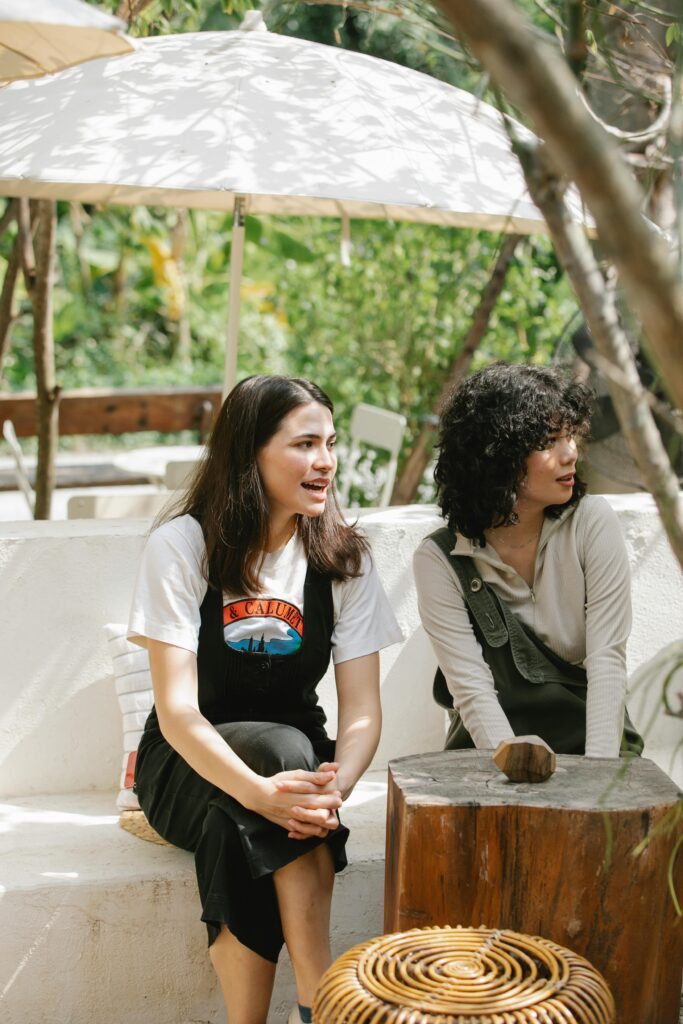 drain-cleaning Young multiethnic women sitting on stone bench and having conversation and attentively looking away